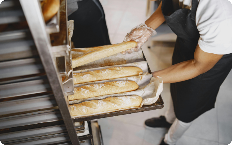Boulanger en train d'enfourner des baguettes de pain